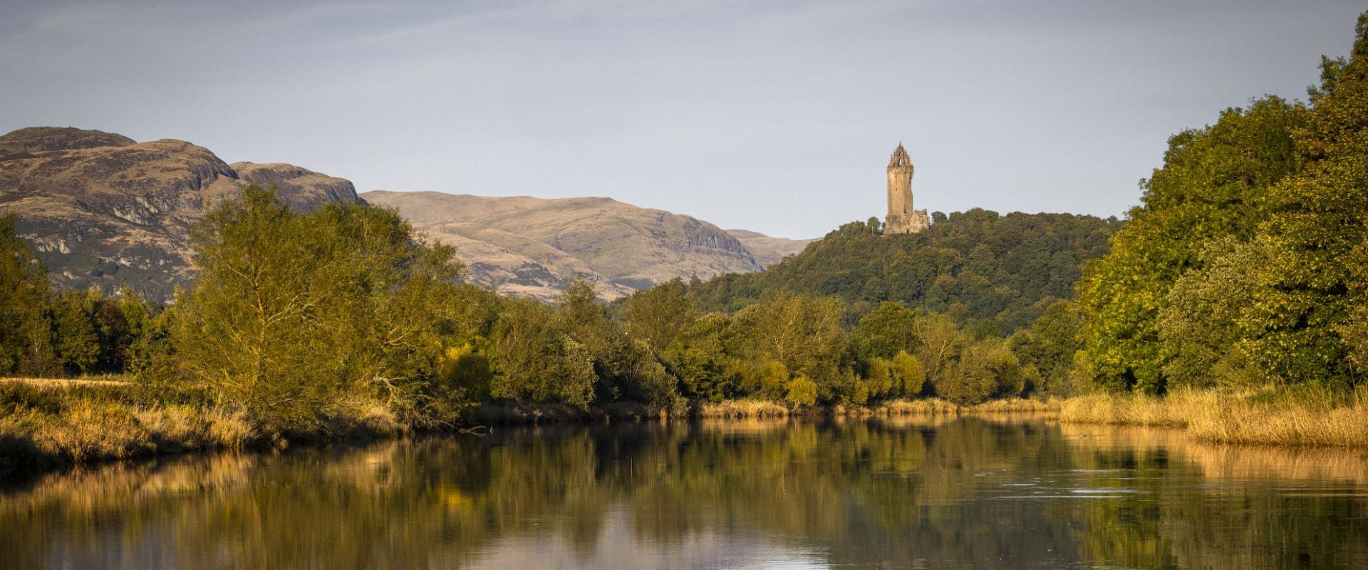 An image of Airthrey Loch within the Stirling University campus, with the Wallace Monument pictured in the background.